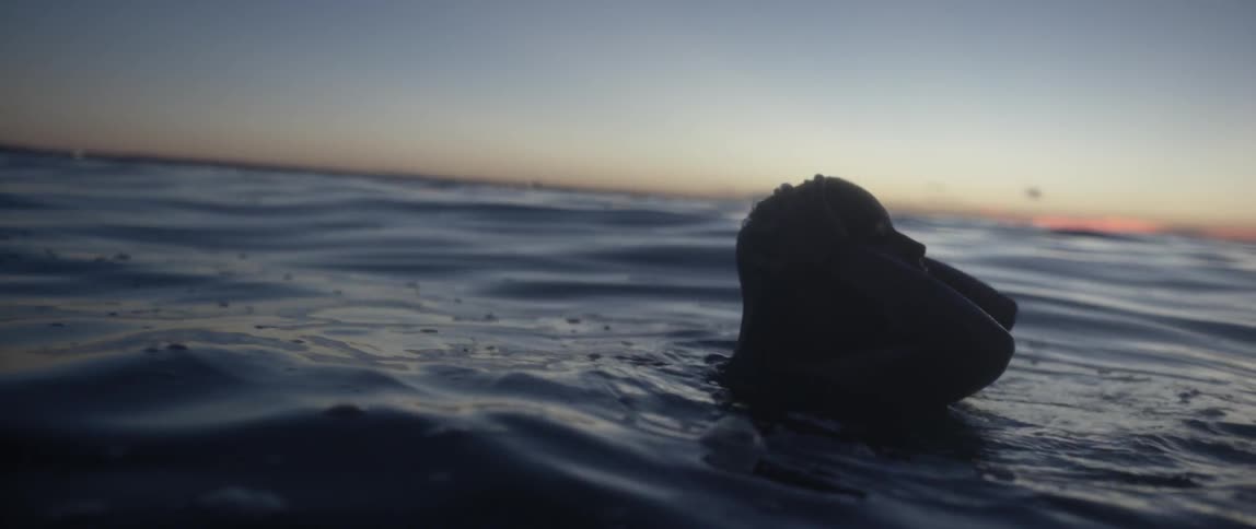 A woman smoothing her wet hair back as she stands in deep water