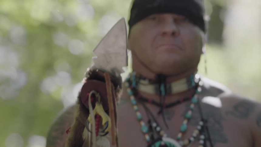 A native american raises a decorated spear