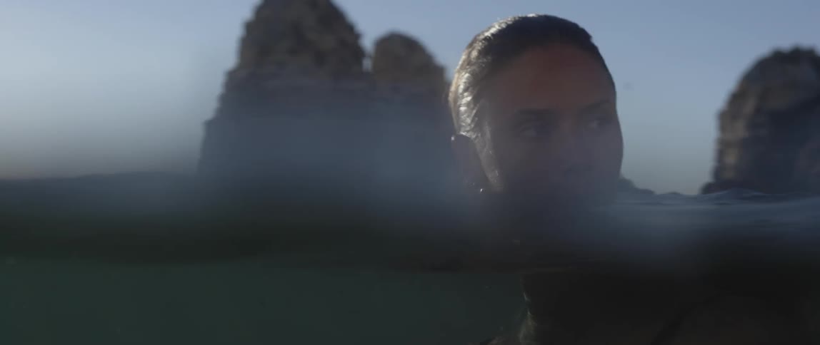 A woman floating in the ocean is looking back