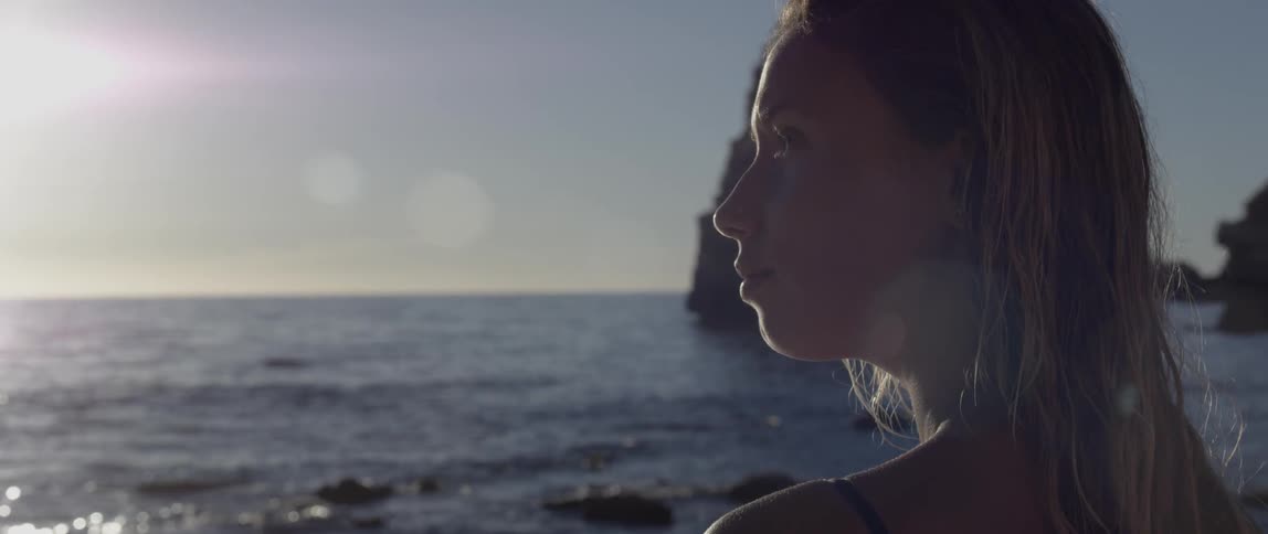 Blonde woman standing on the beach at sunset
