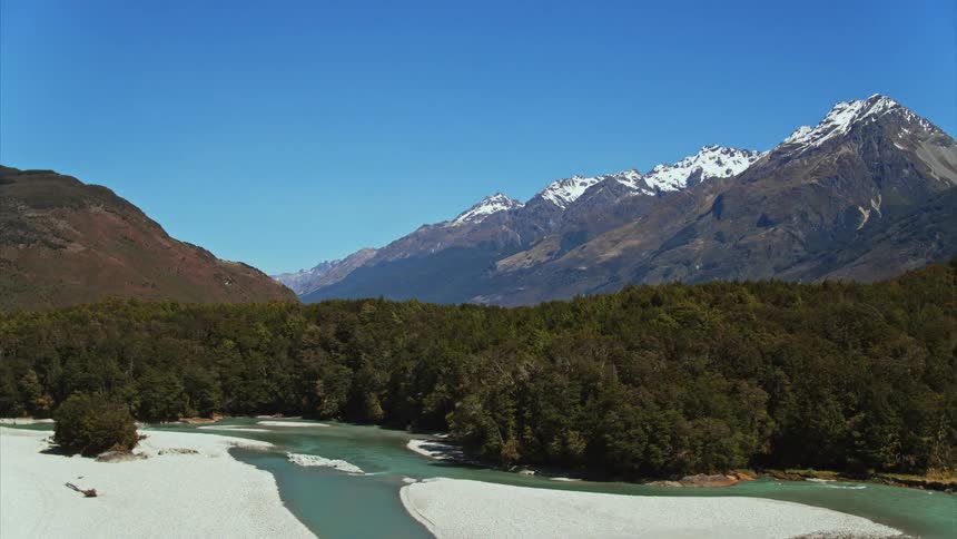 Aerial boom down from native forest to reveal blue alpine river