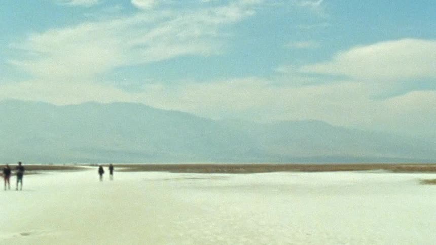 A few people are walking down the beach around the day time