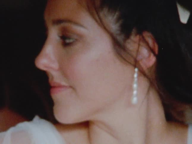 A woman gets help from a friend putting on a white dress caught on vintage film