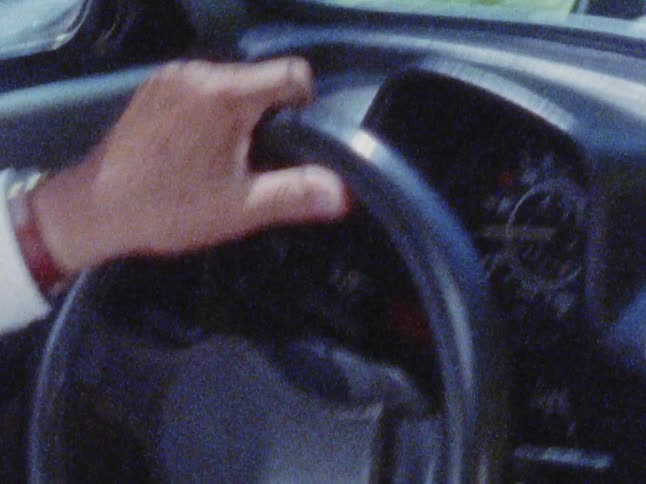 A man is driving a car during the spring time