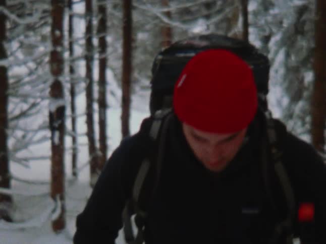 There is a young white man that is hiking in the winter time