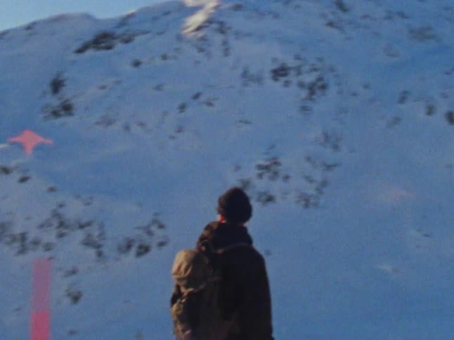 A young white man is skiing down a hill in the winter time