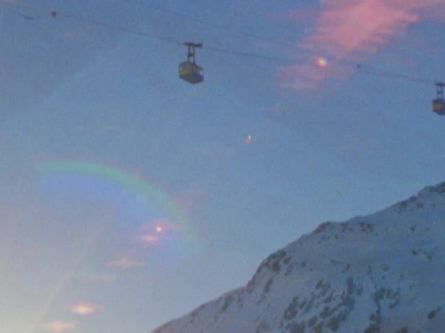 Cable cars moving over a mountain covered in snow at morning caught on vintage film