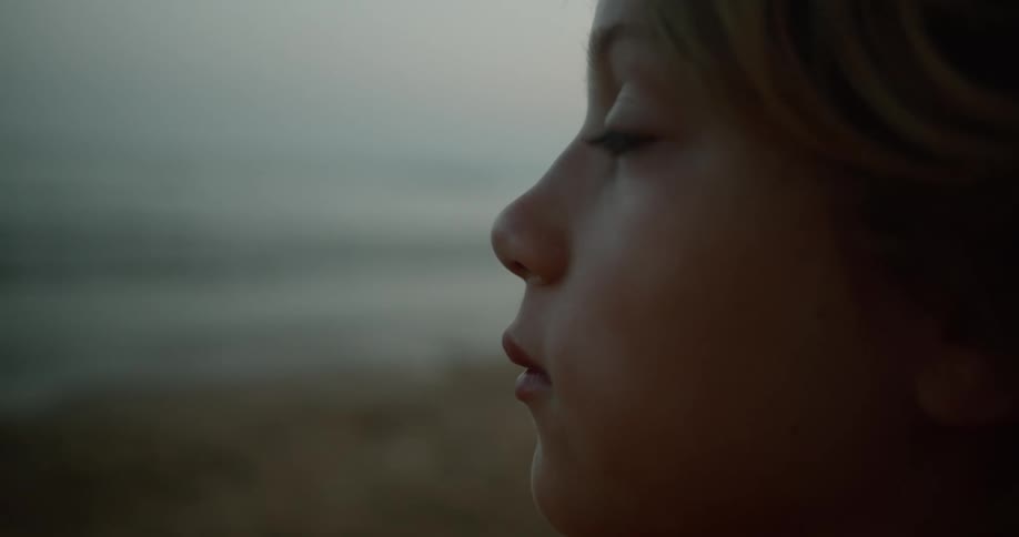 A young white child is at the beach chilling in the day time