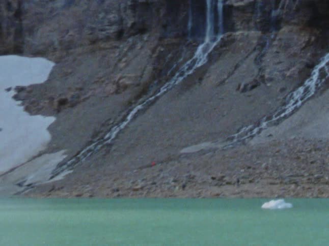 Waterfalls flowing over a canyon next to an icy lake