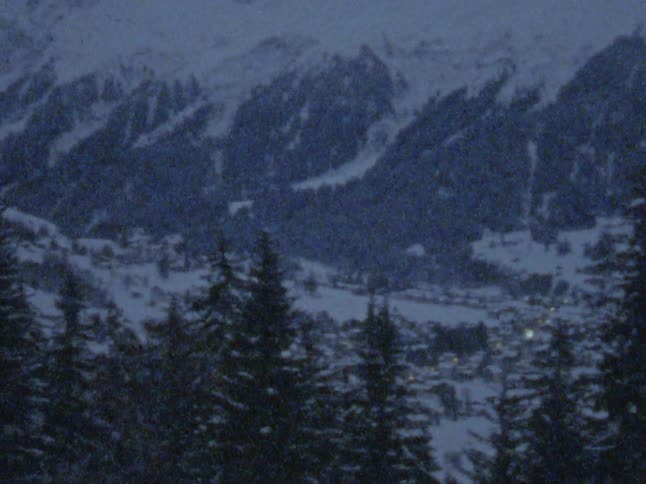 Snow falls onto town and surrounding forest and mountains