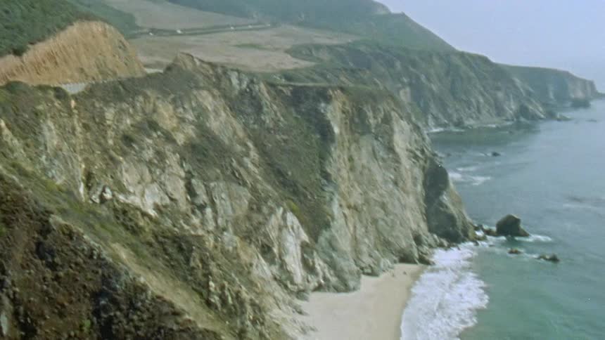 Cars traveling over an arched bridge near a beach