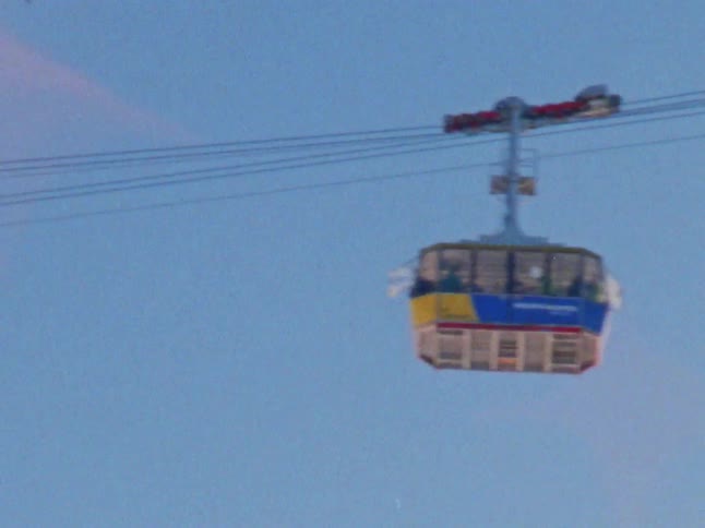A large gondola traveling across wires on a clear day