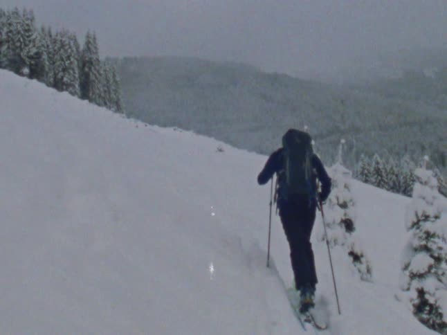 A person trekking on the snow covered slope of a mountain caught on vintage film