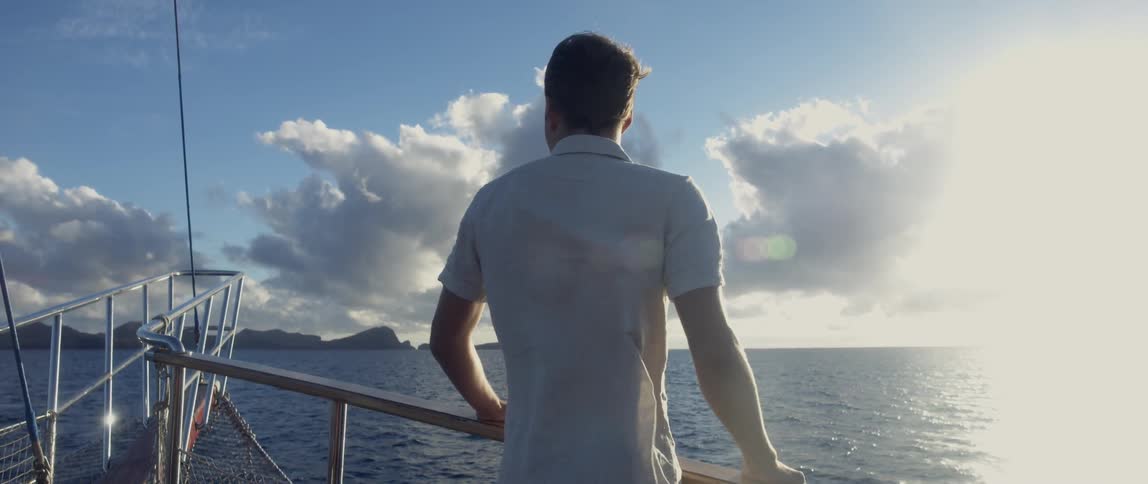 Man in a white shirt standing near a ship's railing