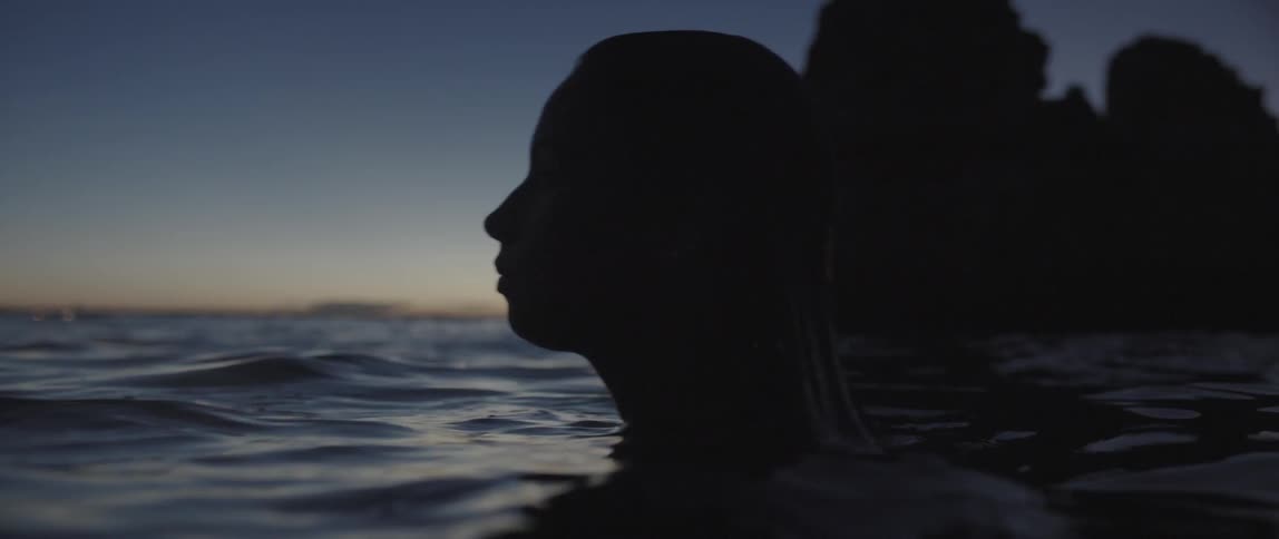 A woman floating in the water at dusk