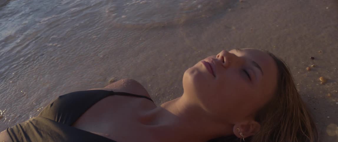 A woman lies on the sand while the waves come in