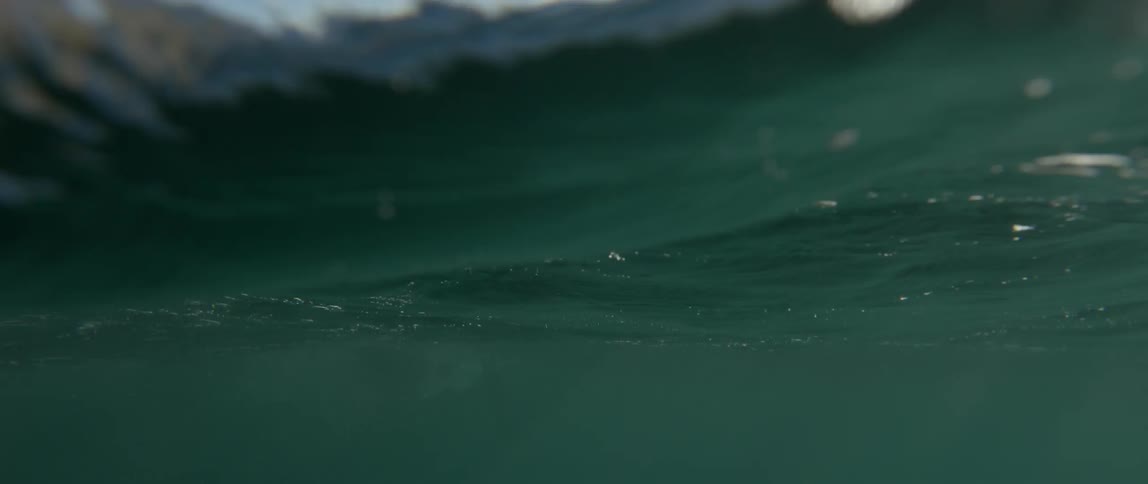 Waves undulate than roll over the camera and a person is briefly seen above the water
