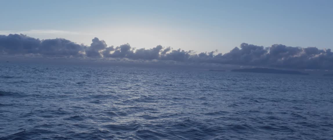 Ocean waters flowing with low clouds on the horizon