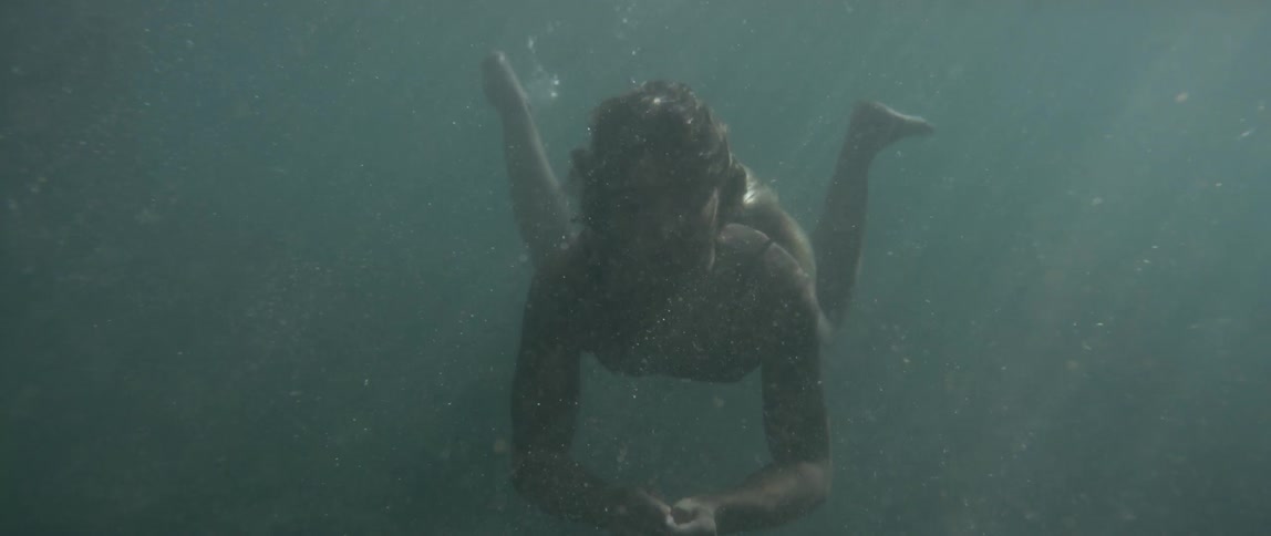 A woman swimming underwater comes up for air