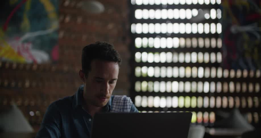 A man rests his chin in his hand and he thinks while looking at a laptop