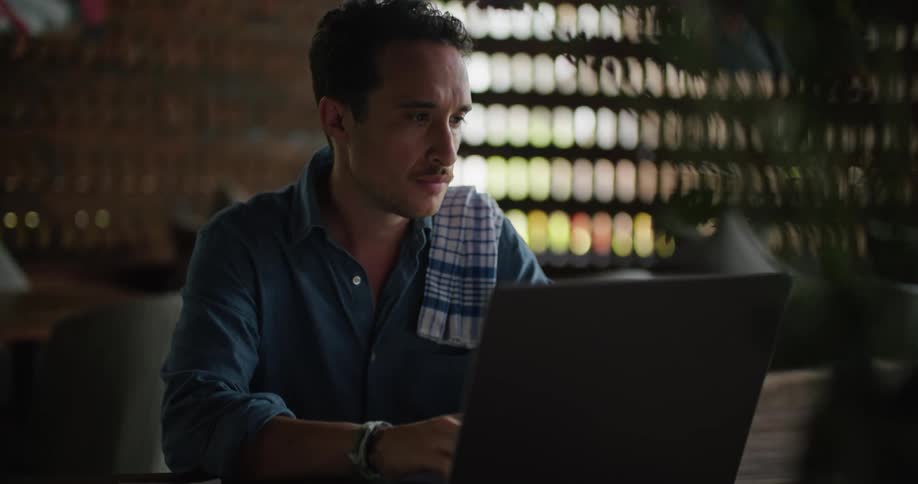 A man works on his laptop at a restaurant bar