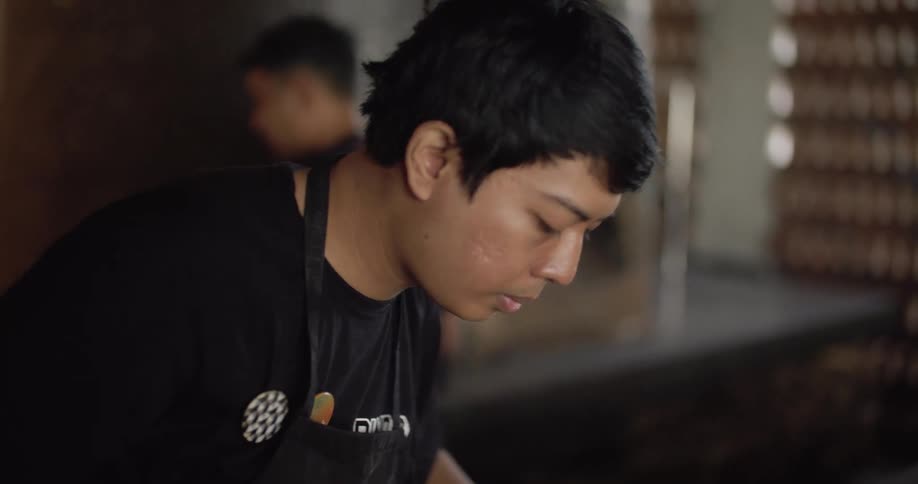 A male restaurant employee making dough in a kitchen