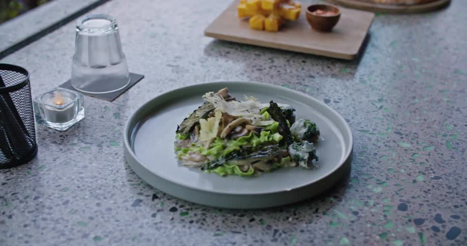A server places a salad near pizza and mozzarella sticks on a table in a restaurant