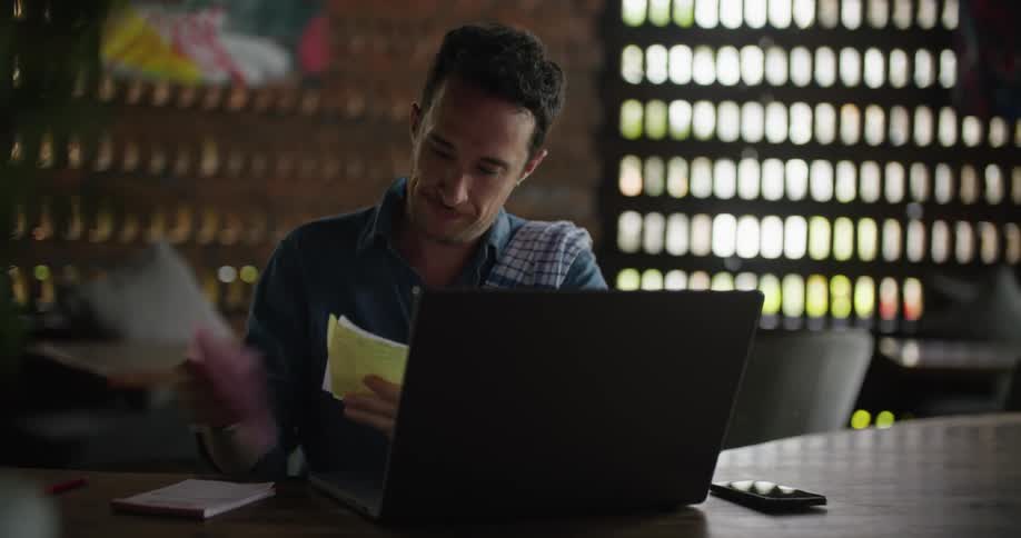 Restaurant owner logging receipts on a laptop in a restaurant
