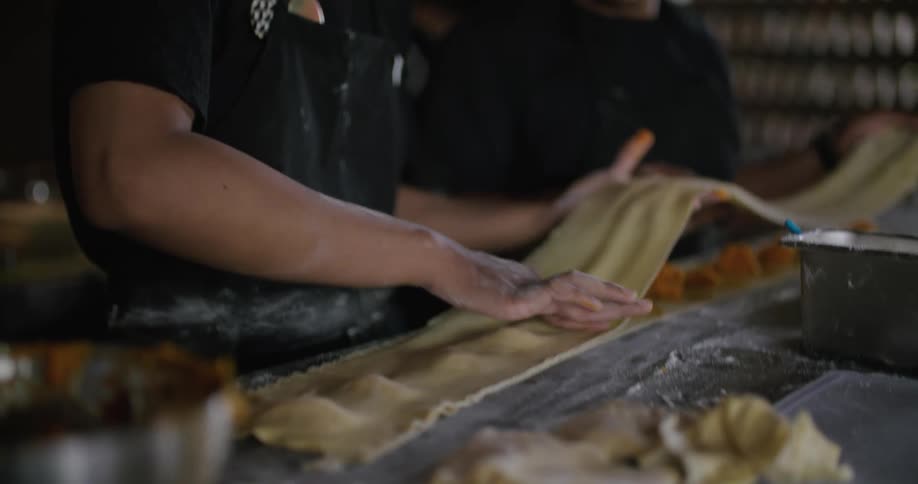 Two cooks prepare pastries on a table in the restaurant kitchen