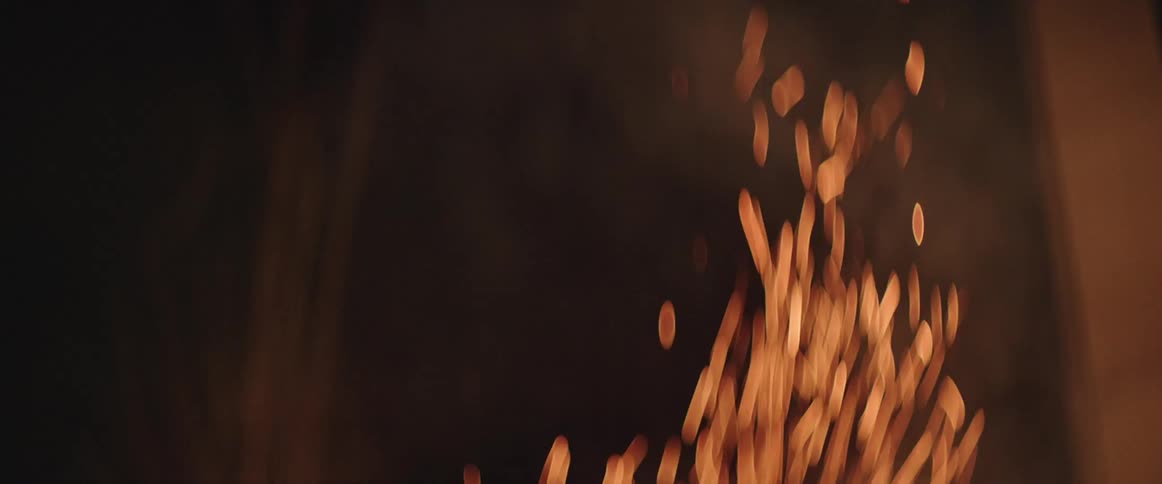 Smoke and sparks rise into the air against a dark background