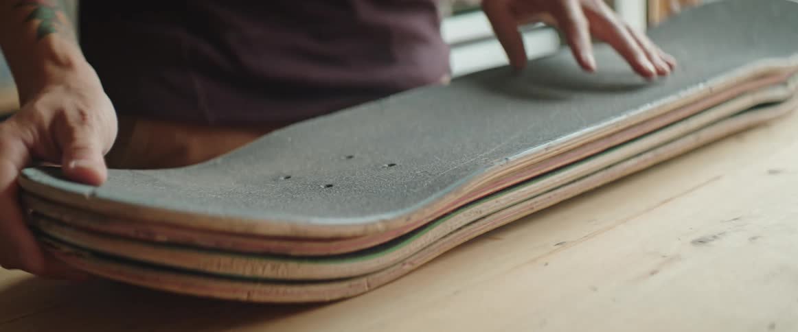 Man carries stack of old skateboard decks to his workshop table
