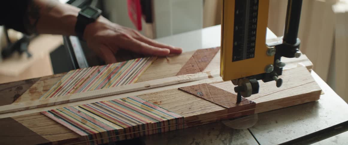 A man is pushing a woodworking project through a bandsaw