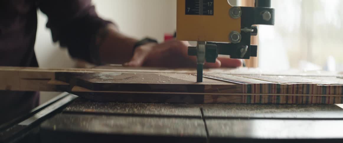 A man is pushing a piece of wood through a saw