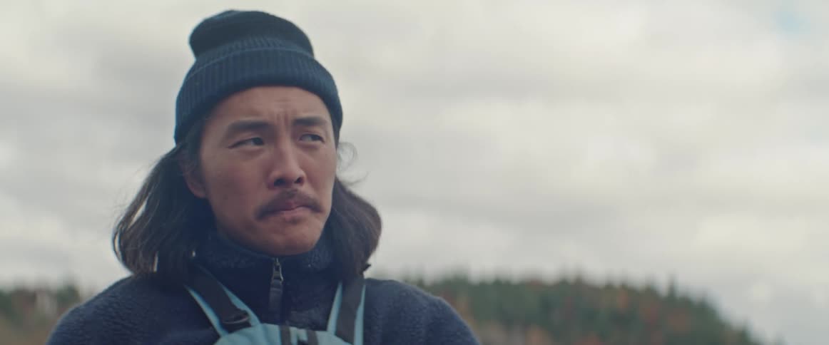 A man paddling on a canoe on a cloudy fall day