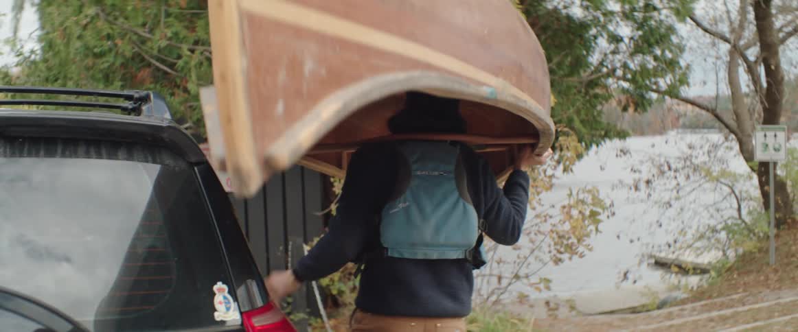 Man lifts canoe from top of suv and carries it toward dock