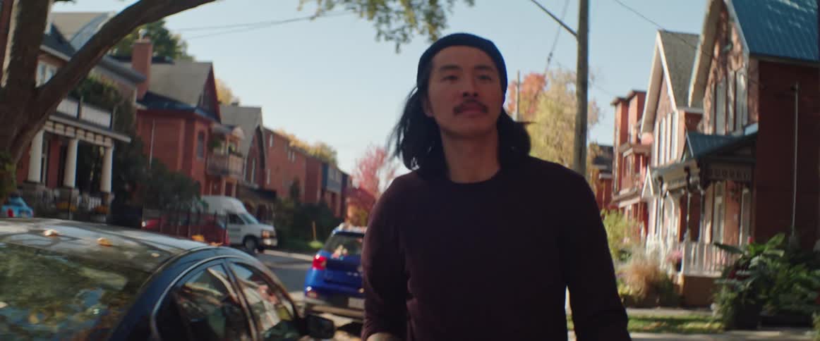 Man carrying disassembled skateboards through the neighborhood during the day