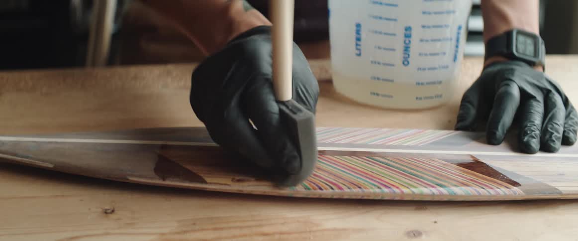 A man paints varnish on a canoe paddle