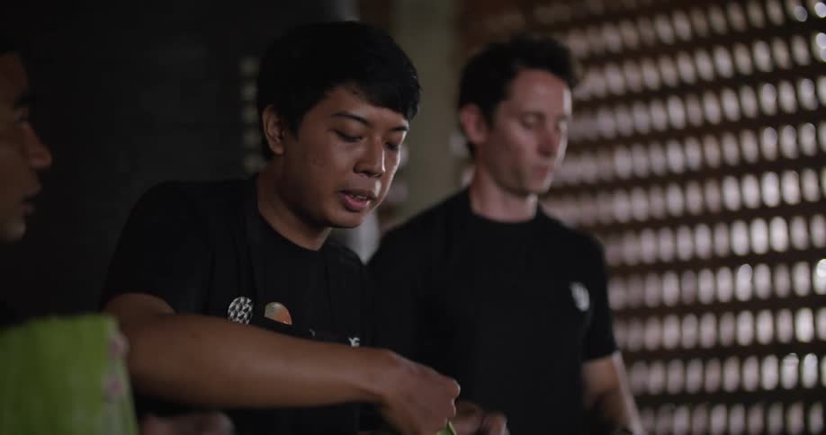 A group of men cook together in a restaurant during the day
