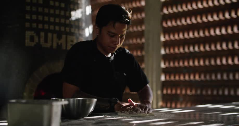 Man kneading dough over the table in the restaurant kitchen