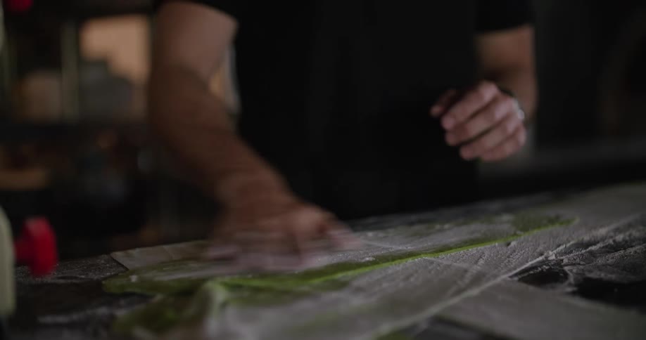 Man sprinkles flour over kneaded dough on the kitchen of a restaurant