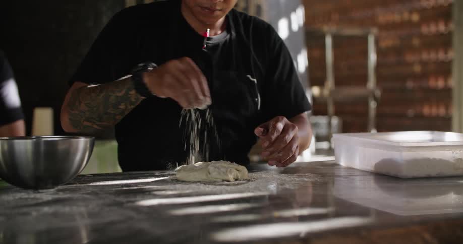 Man works with dough on counter in kitchen