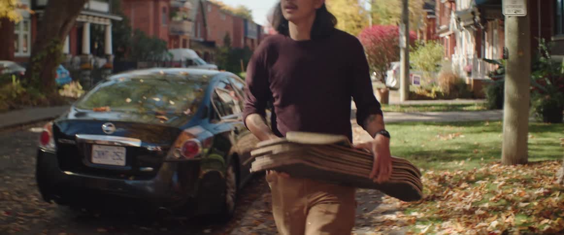 Man carries a stack of skateboard decks through the neighborhood in the morning