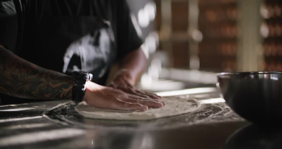 A man is making a pizza with dough