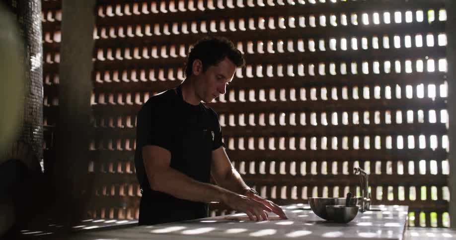 A man prepares dough in a restaurant during the day