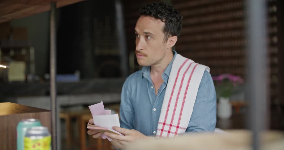 Server hurriedly searches through the orders on a restaurant