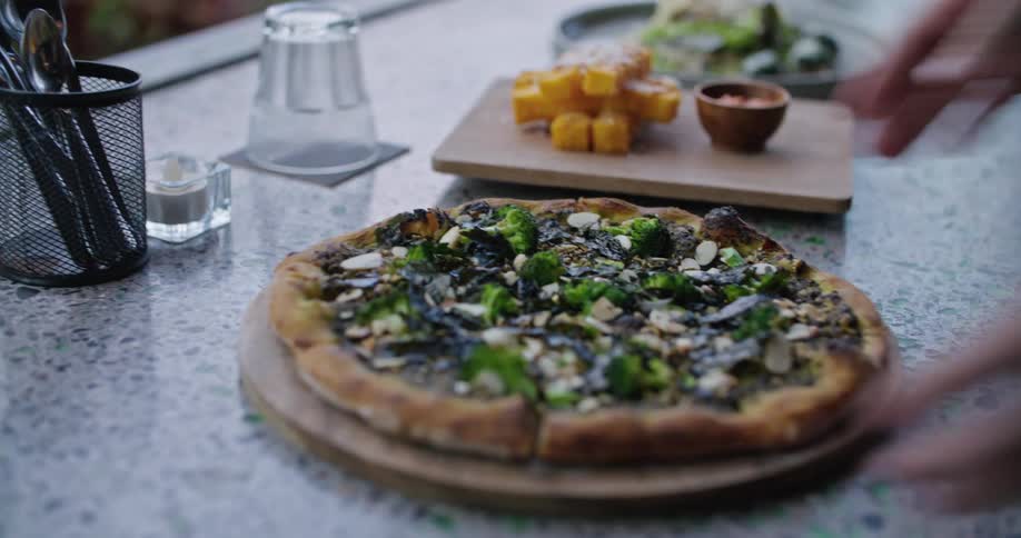 Man serves a freshly cooked pizza on a table at a restaurant