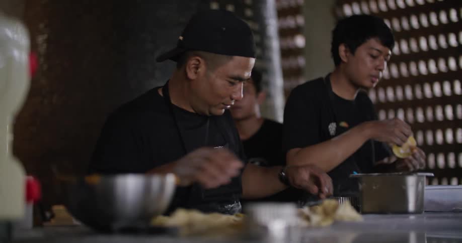 A pair of men prepare pastry together in a restaurant during the day