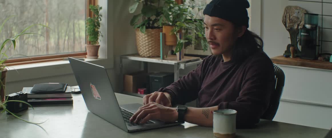 Man sits in front of laptop in home office near window
