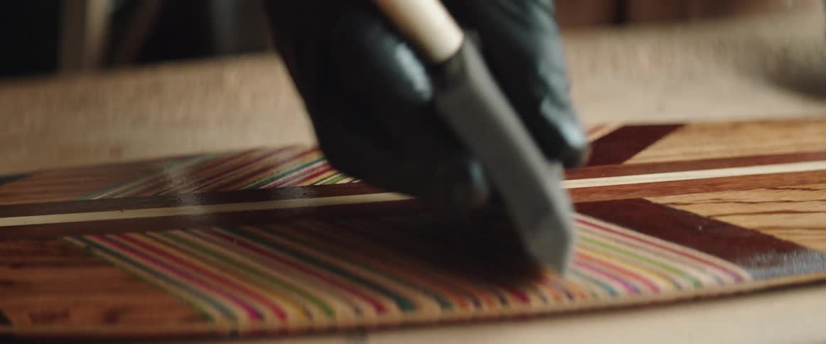 Person wearing glove spreads sealant onto colorful woodwork