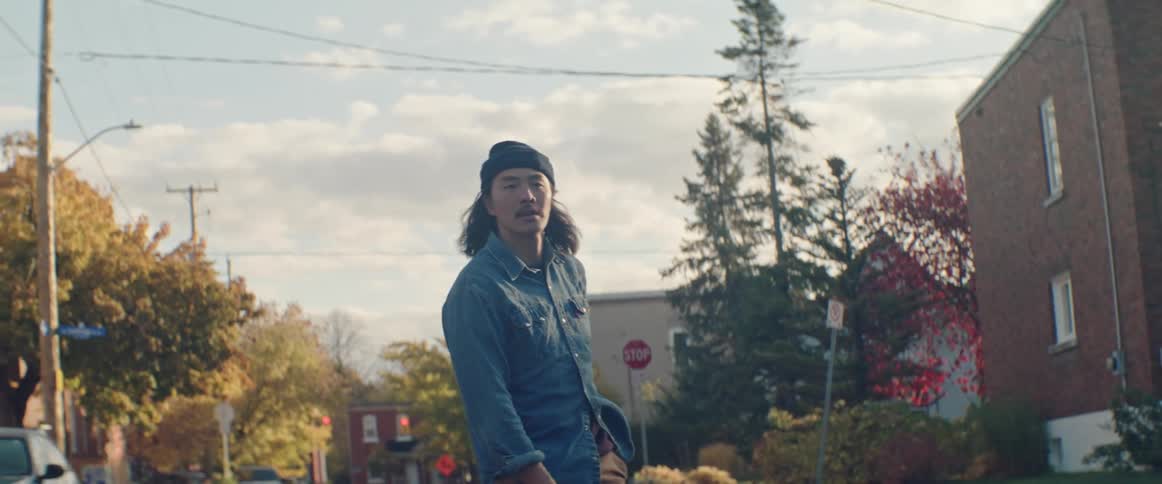 Man rides skateboard down street between apartment buildings